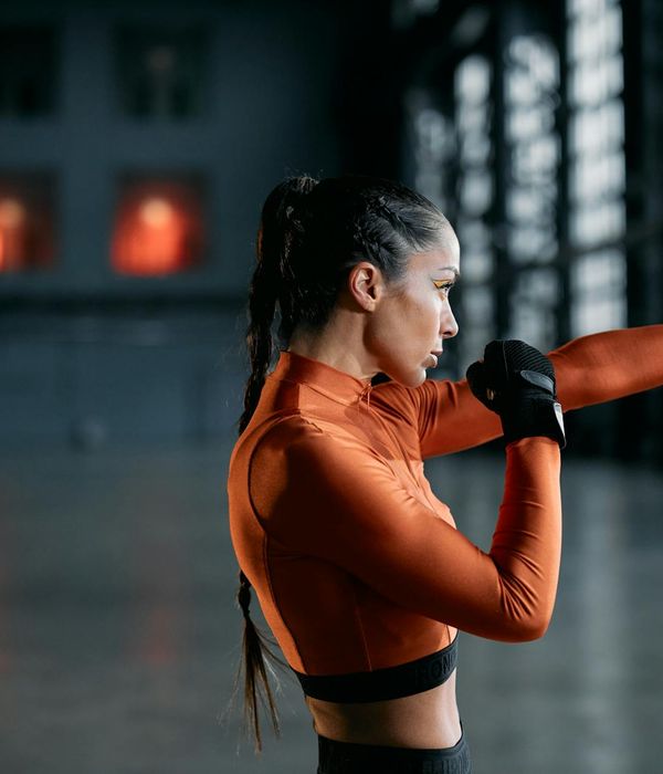 Energetic woman performing a dynamic cardio fitness move in a modern studio.